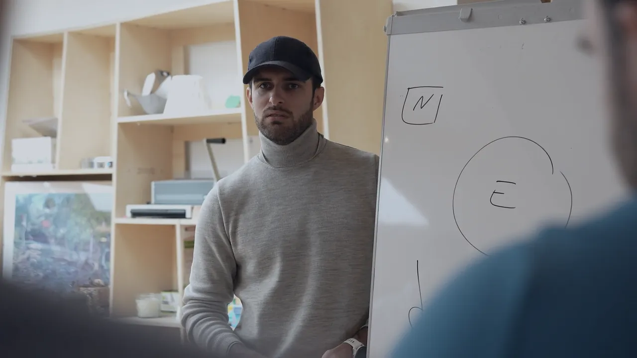 Fabrice Bigot en intervention devant un paperboard, des participants de dos au premier plan.